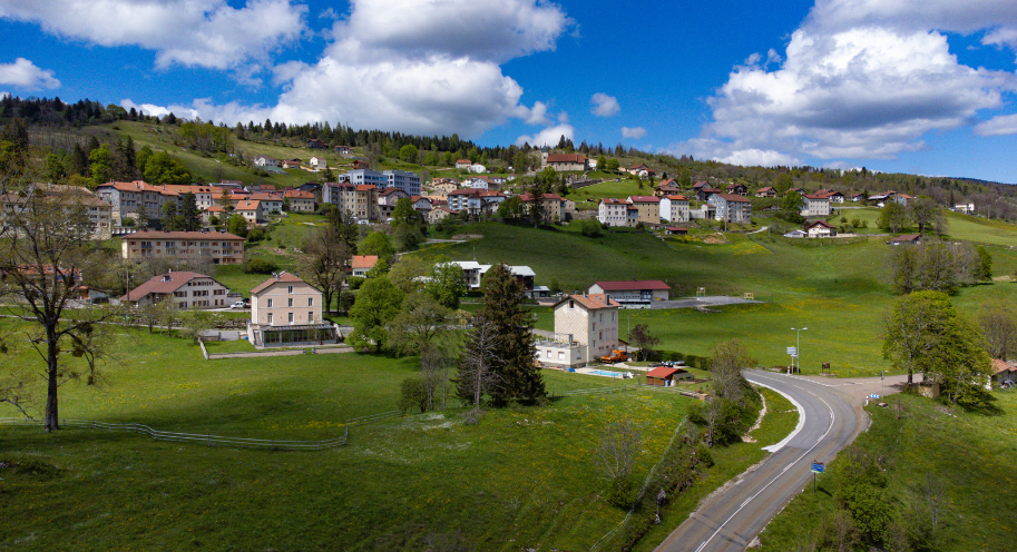 Village du Haut-Jura au milieu des prairies et des collines boisées